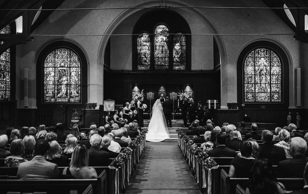 The bride and groom at the church's alter, with guests sitting in pews