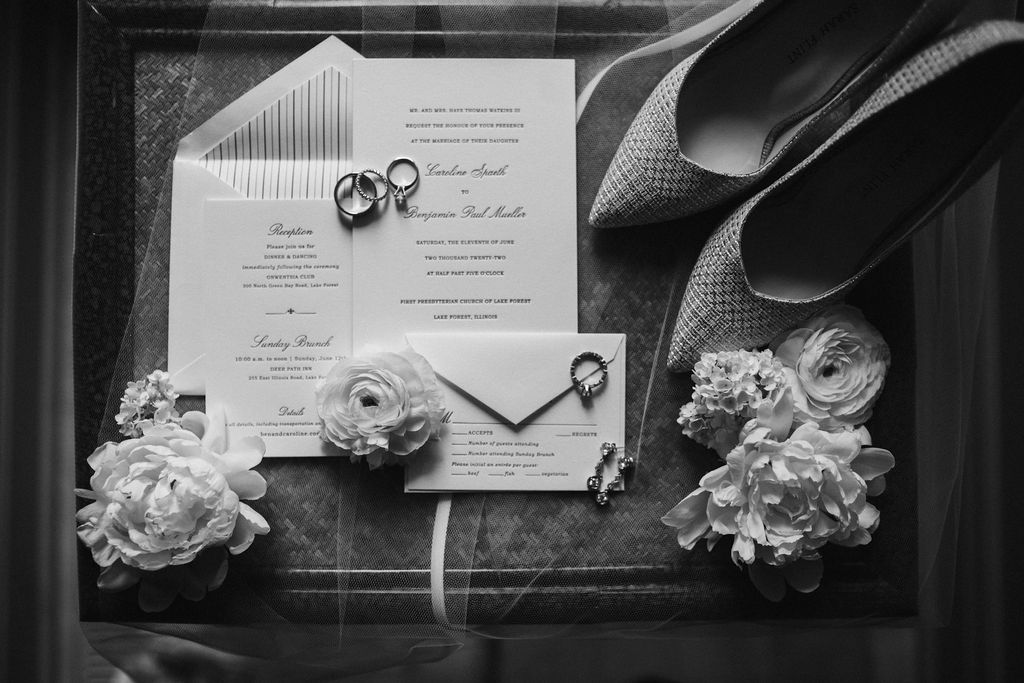 A flat-lay of the invitation suite, wedding bands, and the bride's wedding day jewelry and shoes
