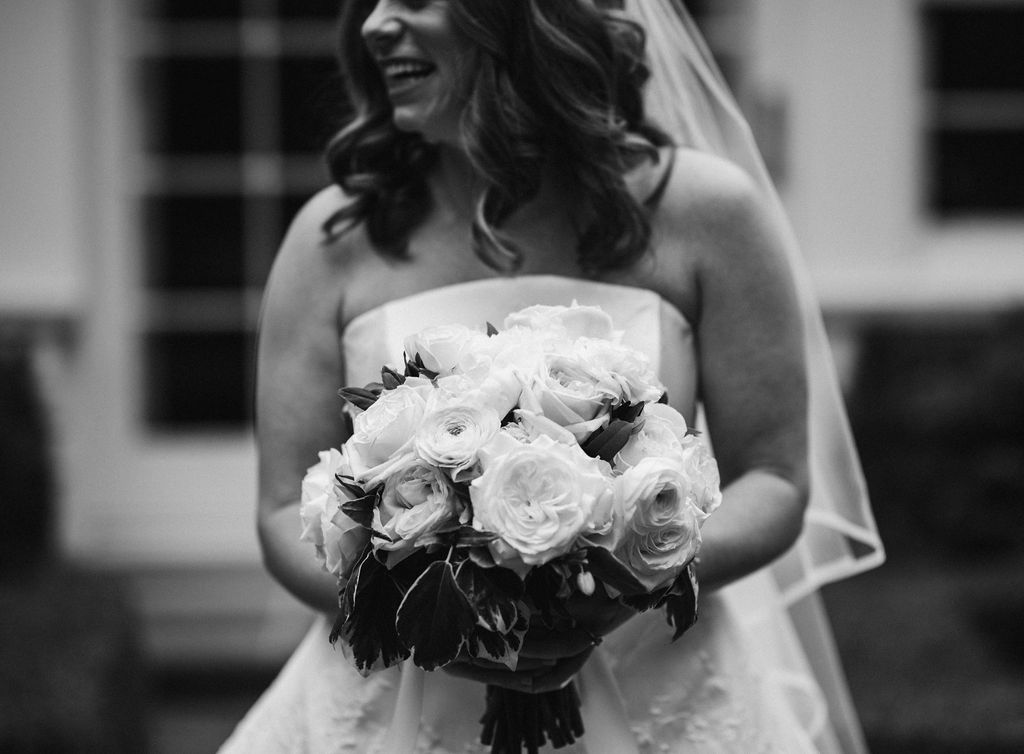 Bride smiling and holding bouquet of white roses and peonies