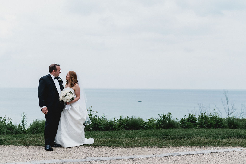 The bride and groom pose at the top of the beach overlooking Lake Michigan